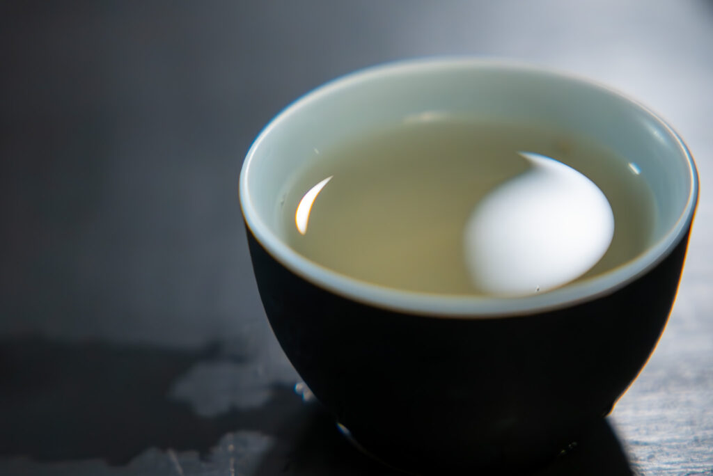 The liquor of the Yunnan Silver Needle white tea in a pale blue and black cup