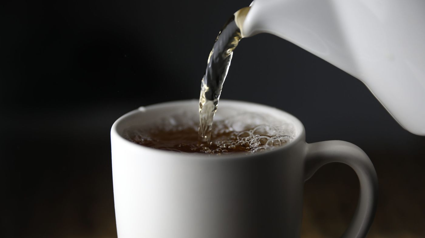 Brewed Miyabi Sencha green tea from Kettl being poured from a kettle into a white porcelain cup